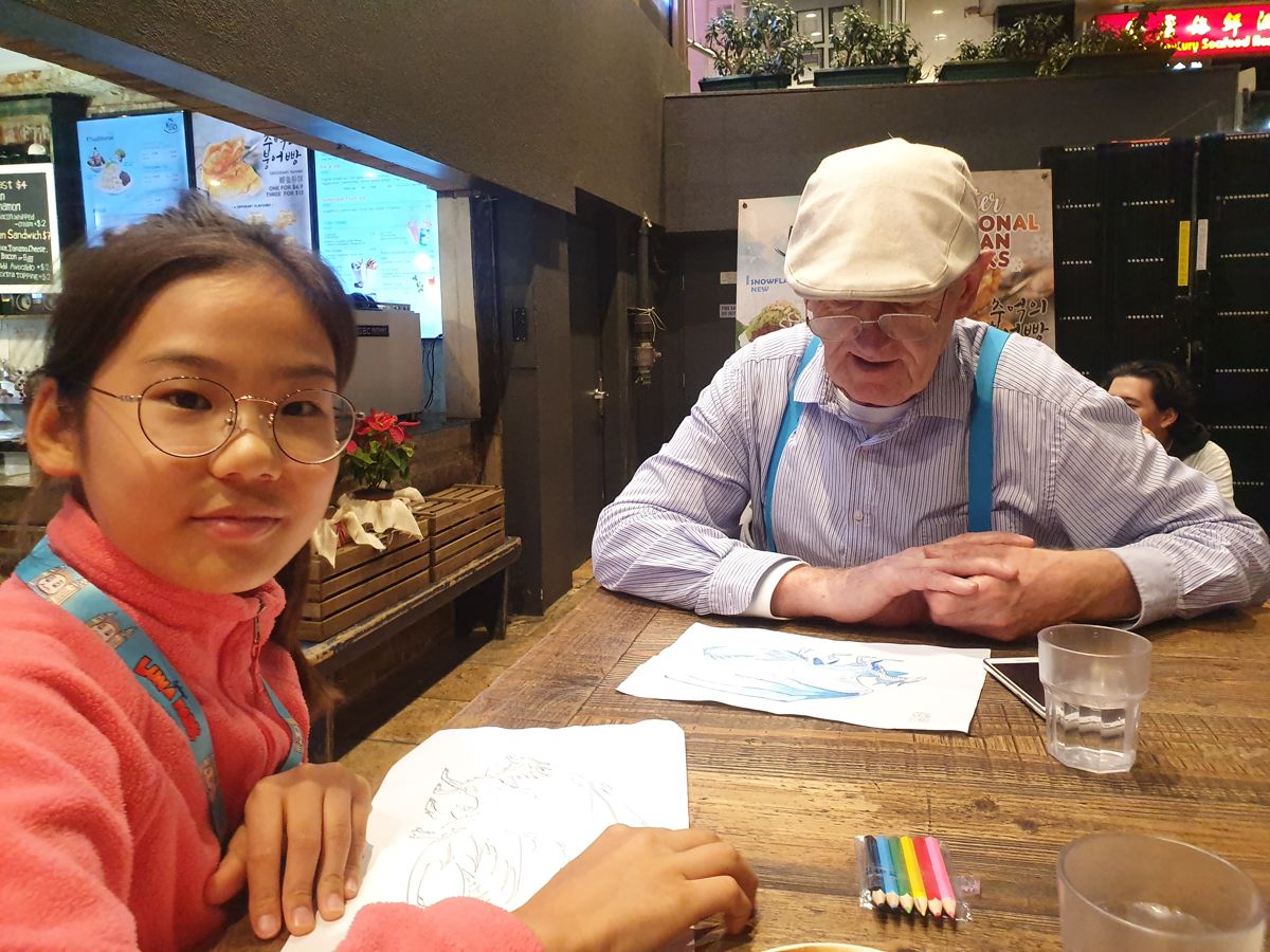 Drawing together with her friend at a café table