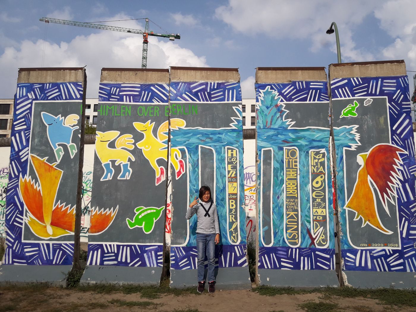 Ari in front of a painted section of the Berlin Wall
