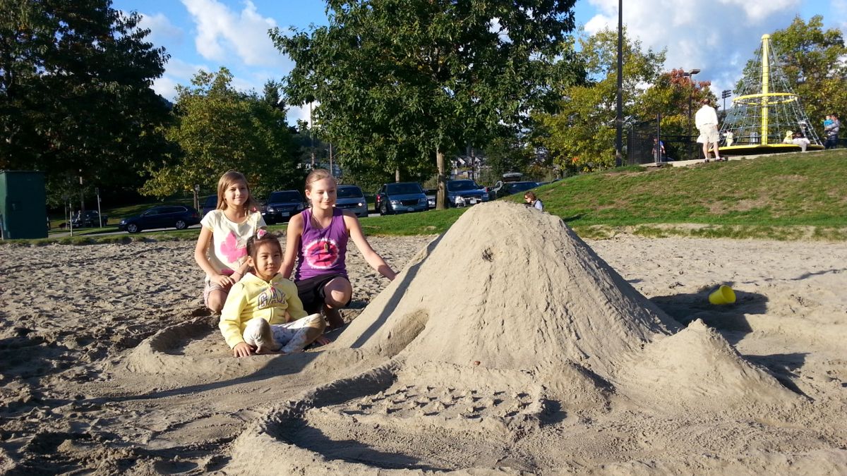 Children building a sand mountain at a Vancouver playground
